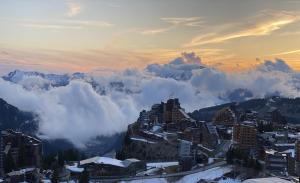 a view of a city in the mountains with clouds at Antarès Location Avoriaz in Avoriaz
