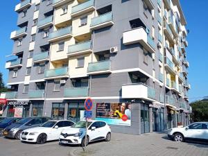 un edificio alto con coches estacionados frente a él en Apartman Best, en Doboj