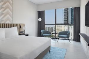 a hotel room with a bed and two chairs at Courtyard by Marriott World Trade Centre, Dubai in Dubai
