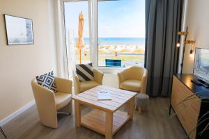 ein Wohnzimmer mit einem Tisch, Stühlen und einem Fenster in der Unterkunft Studio 16 "Sandmeer" mit Meerblick in Grömitz