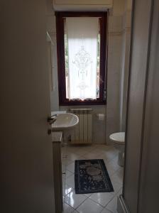 een badkamer met een wastafel, een toilet en een raam bij A casa di Ale in Castiglione della Pescaia