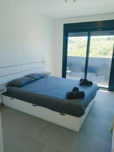 een groot bed in een kamer met een groot raam bij New build Blue sunset large 2 bed apt in Manilva