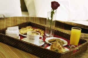 a tray with breakfast foods and a vase with a rose at MIL810 Ushuaia Hotel in Ushuaia