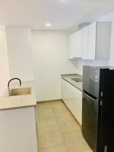 a kitchen with a black refrigerator and white cabinets at Urban Village Night Stay in Phnom Penh