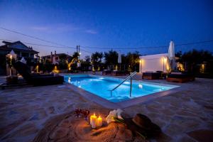 a swimming pool at night with candles next to it at Villa Ellania in Ambelókipoi