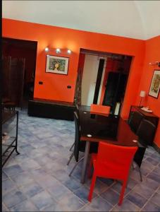 une salle à manger avec une table et un mur rouge dans l'établissement Dammuso SoleLuna., à Terrasini