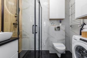 ein Badezimmer mit einem WC, einem Waschbecken und einer Waschmaschine in der Unterkunft Sea Resort Kropli Bałtyku Apartment with Terrace by Renters in Darłowo