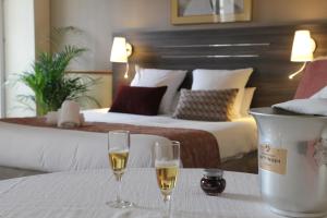 リュクスイユ・レ・バンにあるHOTEL CERISE - LES SOURCES Luxeuil-les-Bainsのホテルの部屋のテーブルの上にシャンパン2杯