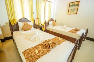 two beds sitting next to each other in a room at Treasure Hotel Laos in Luang Prabang