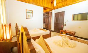 a hotel room with two beds and a tv at Treasure Hotel Laos in Luang Prabang