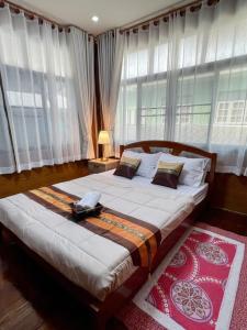 a bedroom with a large bed with windows at Tintin home in Chiang Rai