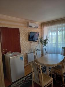 eine Küche mit einem Tisch und einem TV an der Wand in der Unterkunft Готель Поділля in Shestakovka