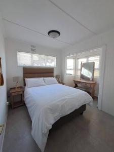 una camera bianca con un grande letto e uno specchio di Die Boomhuis. Pearly Beach a Pearly Beach