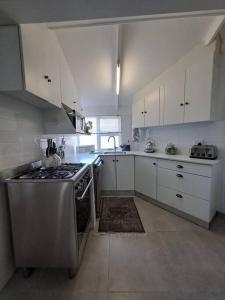 a kitchen with a stainless steel stove and white cabinets at Die Boomhuis. Pearly Beach in Pearly Beach