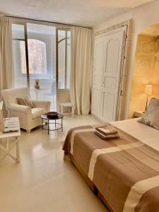 a bedroom with a bed and a chair and a couch at La Maison Plume, Appart Boutique in Saint-Rémy-de-Provence