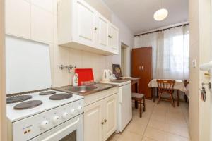 a kitchen with white cabinets and a white stove top oven at Sole Solei apartman 2 - Meljine in Meljine