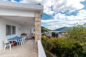 a white house with a blue table and chairs on a balcony at Sole Solei apartman 2 - Meljine in Meljine