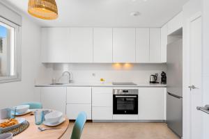 una cucina con mobili bianchi e un tavolo di legno di MEDANO4YOU Tenerife Breeze a El Médano