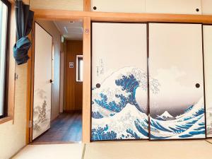 a sliding glass door with a painting of a wave at 302东京中心全新装修宽敞明亮的公寓 3分钟步行路程到门前仲町站 两条地铁线直达东京上野新宿 in Tokyo