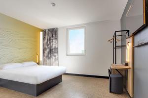 une chambre d'hôtel avec un lit et une fenêtre dans l'établissement B&B HOTEL Saintes, à Saintes