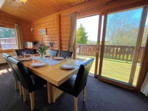 a dining room table with chairs and a large window at Beautiful Norwegian Lodge in Kippford with Garden Pass the Keys in Dalbeattie