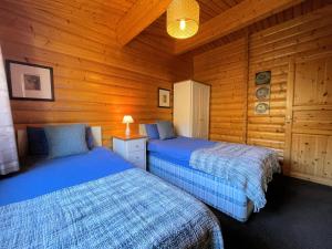 two beds in a room with wooden walls at Beautiful Norwegian Lodge in Kippford with Garden Pass the Keys in Dalbeattie