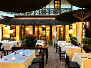 a restaurant with tables and chairs with white tablecloths at Rachamankha Hotel in Chiang Mai