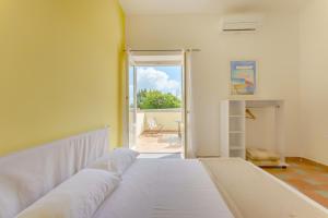 Cama blanca en habitación con puerta abierta en Le Grand Bleu - Gioia Apartments, en Procida