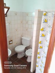 uma pequena casa de banho com um WC e uma cortina de chuveiro em I Casa de invitados cerquita de la playa buenas olas em La Aguada
