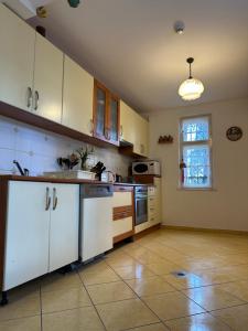 cocina con armarios blancos y suelo de baldosa en Party Villa Holiday Rent Balatonfoldvar, en Balatonföldvár