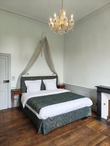 een slaapkamer met een groot bed en een kroonluchter bij Le Château des Portes 