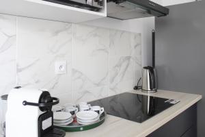 - une cuisine avec des murs en marbre blanc et un comptoir dans l'établissement Charming house with an outdoor terrace, à Ivry-sur-Seine
