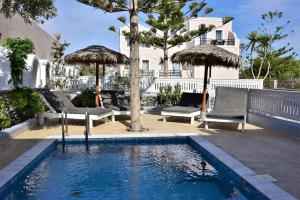 una piscina con dos sillas y sombrillas en Villa Serene, en Kamari