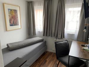 a bed in a room with a chair and windows at Hotel Restaurant Rössle in Calw