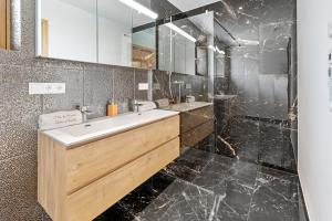ein Bad mit einem Waschbecken und einem Spiegel in der Unterkunft Luxus Chalet Max in Glanz an der Weinstraße 