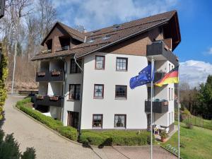a large white building with a flag in front of it at Haus Sachsensteinblick Ferienwohnung Sonnenschein in Bad Sachsa +28 photos