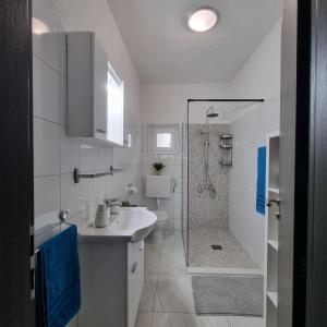 a white bathroom with a sink and a shower at Holiday House DA & DO in Pakoštane