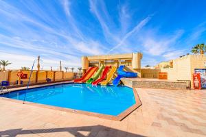 a pool with a slide in front of a resort at Golden Beach Resort in Hurghada