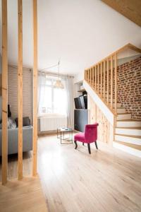 a living room with a staircase and a red chair at La Longère Gasiaquoise in Gauchy