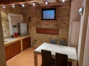 a kitchen with a table and a tv on a brick wall at Caolzio18 in CastellʼArquato