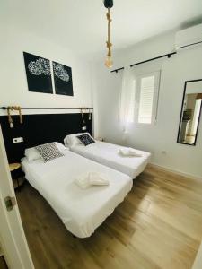 twee bedden in een kamer met witte muren en houten vloeren bij Piso San Eloy - Centro de Cordoba in Córdoba