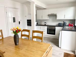 a kitchen with a table with a vase of flowers on it at Charming Seaside Cottage in Leigh-on-Sea in Southend-on-Sea