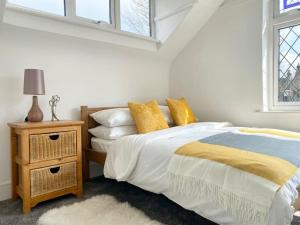 a white bedroom with a bed and a night stand at Charming Seaside Cottage in Leigh-on-Sea in Southend-on-Sea