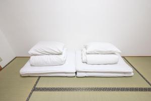 a bed with white sheets and pillows on the floor at Osaka U-Shuku in Osaka