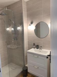La salle de bains est pourvue d'une douche, d'un lavabo et d'un miroir. dans l'établissement Appartement T2 - 50m de la Mer - Parking - Wifi, à Courseulles-sur-Mer