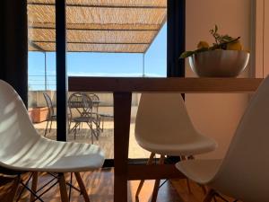 a dining room table with white chairs and a table with a view at PetraSicula Apartment in Acitrezza