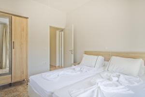 a large white bed with white sheets and pillows at Karpathos City View Apartments in Karpathos
