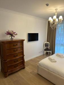 ein Schlafzimmer mit einem Bett, einer Kommode und einem TV in der Unterkunft BIRUTE AVENUE 2 BEDROOMS in Palanga
