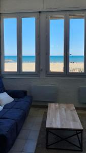 - un salon avec un canapé et une vue sur la plage dans l'établissement Maison sur mer Palavas, à Palavas-les-Flots