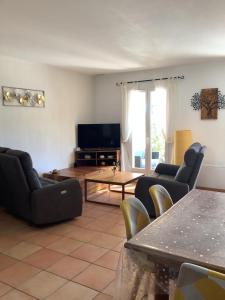 a living room with couches and a tv and a table at Les Oliviers in Mallemort